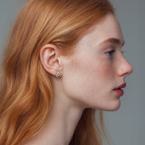 Hjerte-øreringe i guld - geometriske symbolske smykker på kærlighed eller som julehjerte, vist fra siden på model - Livva