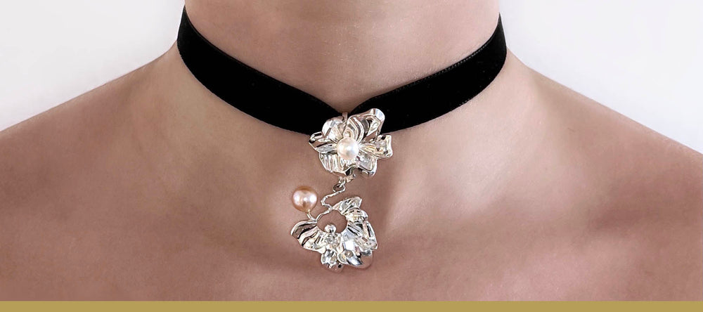 Statement necklace with a flower pendant in sterling silver with pearls on a velour ribbon shown on model.