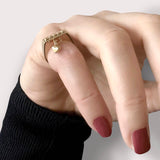 Hjerte charm ring – Elegant firkantet design i guld med små nitter og et hjerteformet vedhæng, vist på hånd – Livva.