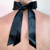 Black satin ribbon as closure for a necklace - tied to a bow and seen from behind on model - Livva Østerby.