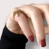 Charm heart ring – Sleek square design in gold with tiny studs and a heart dangle charm, shown on hand – Livva Østerby.
