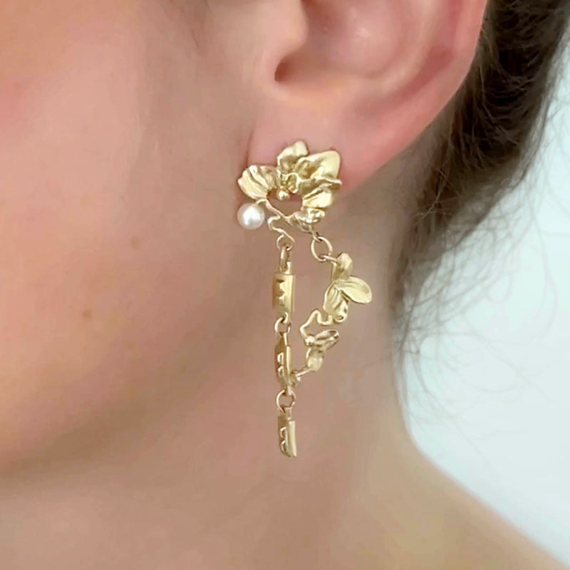 Gold floral earrings - Organic jewellery design in gold, with surreal leaves, chains, and a white pearl – on ear - Livva