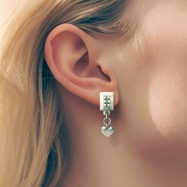 Heart drop earrings – A square design with tiny studs and a dangling heart in sterling silver on model – Livva Østerby.