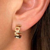 Love Love bogstav ørering hvor store bogstaver er sat sammen i guld, vist zoomet ind på øre - Livva