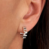 Bgstav ørering hvor ordene LOVE LOVE er sammensat som udskårne bogstaver i sterling sølv, zoomet ind på øre - Livva