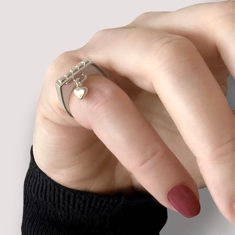 Ring with heart charm – Sleek square design in sterling silver with tiny studs and a heart dangle charm, on hand – Livva Østerby.
