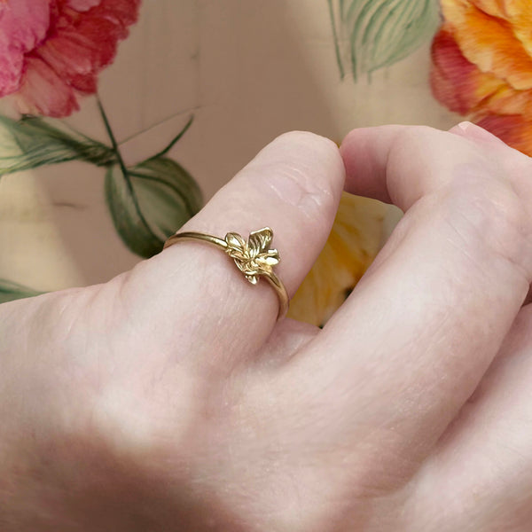 Small flower ring – Organic jewellery in gold with nature-inspired delicate leaves on a thin ring band – shown on finger - Livva