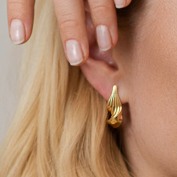 Snoede øreringe - Luksuriøst organisk dansk design i et skulpturelt twist i 18k guld med rillede linjer, på øre - Livva