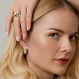 Snoede sølvøreringe og ring - organisk dansk design i et skulpturelt twist med rillede linjer, vist på model – Livva