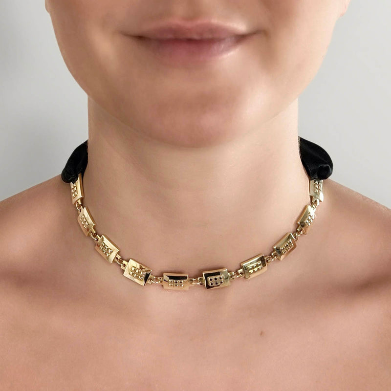 Square chain necklace – Chunky gold design with tiny studs & elegant black satin ribbon closure on model – Livva Østerby.