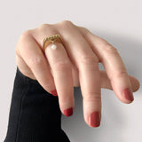 Square ring in gold – Sleek square design with tiny studs & a snow quartz dangle charm shown on hand – Livva Østerby.