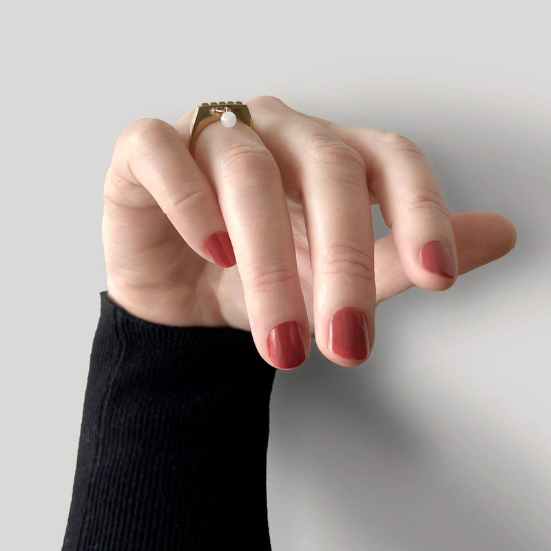 Square ring in gold – Sleek square design with tiny studs & a snow quartz dangle charm on hand from the front – Livva Østerby.