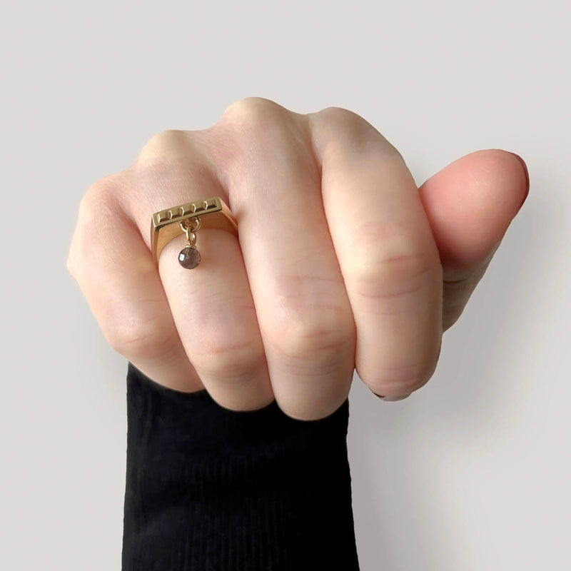 Gold square ring – Sleek square design with tiny studs and a smoky quartz dangle charm on hand from above – Livva Østerby.