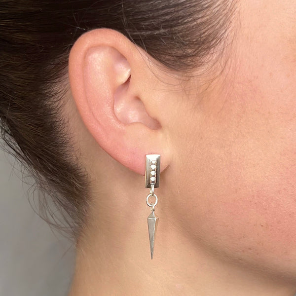 Spike earrings silver – A sleek square design with tiny studs and a dangling spike in sterling silver on model – Livva Østerby.