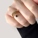 Square ring gold – A sleek square design with tiny studs and a black spinel dangle charm on hand close up – Livva Østerby.