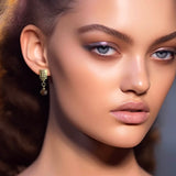 Firkantede øreringe i guld med små nitter og dinglende facetslebet ædelsten af røgkvarts, vist på model- Livva