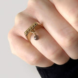 Firkantet ring - Smal aflang charm ring i guld med dinglende ædelsten af røgkvarts, vist på hånd - Livva