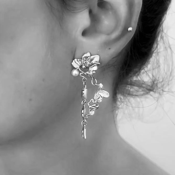 Video of surreal organic chain earring dangling in sterling silver - Small leaves and a freshwater pearl on model.