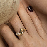 Wavy guld ring – Unikt dansk smykkedesign i 18k guld af naturlige organiske bølger, der omgiver en fin hvid Akoya saltvandsperle, vist på hånd – Livva 